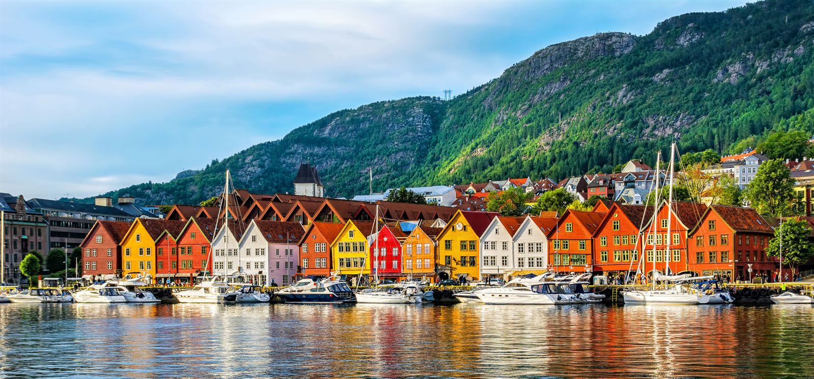Colorful wooden houses of Bryggen along Bergen harbor, with a green mountain behind