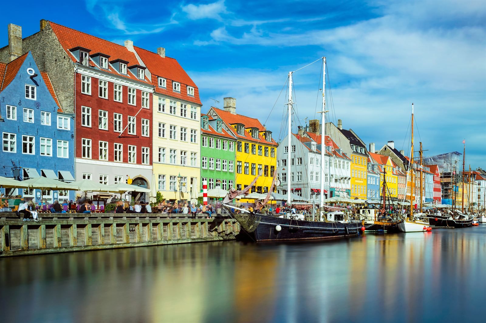 Colorful townhouses and wooden sailing ships along the Nyhavn canal in Copenhagen