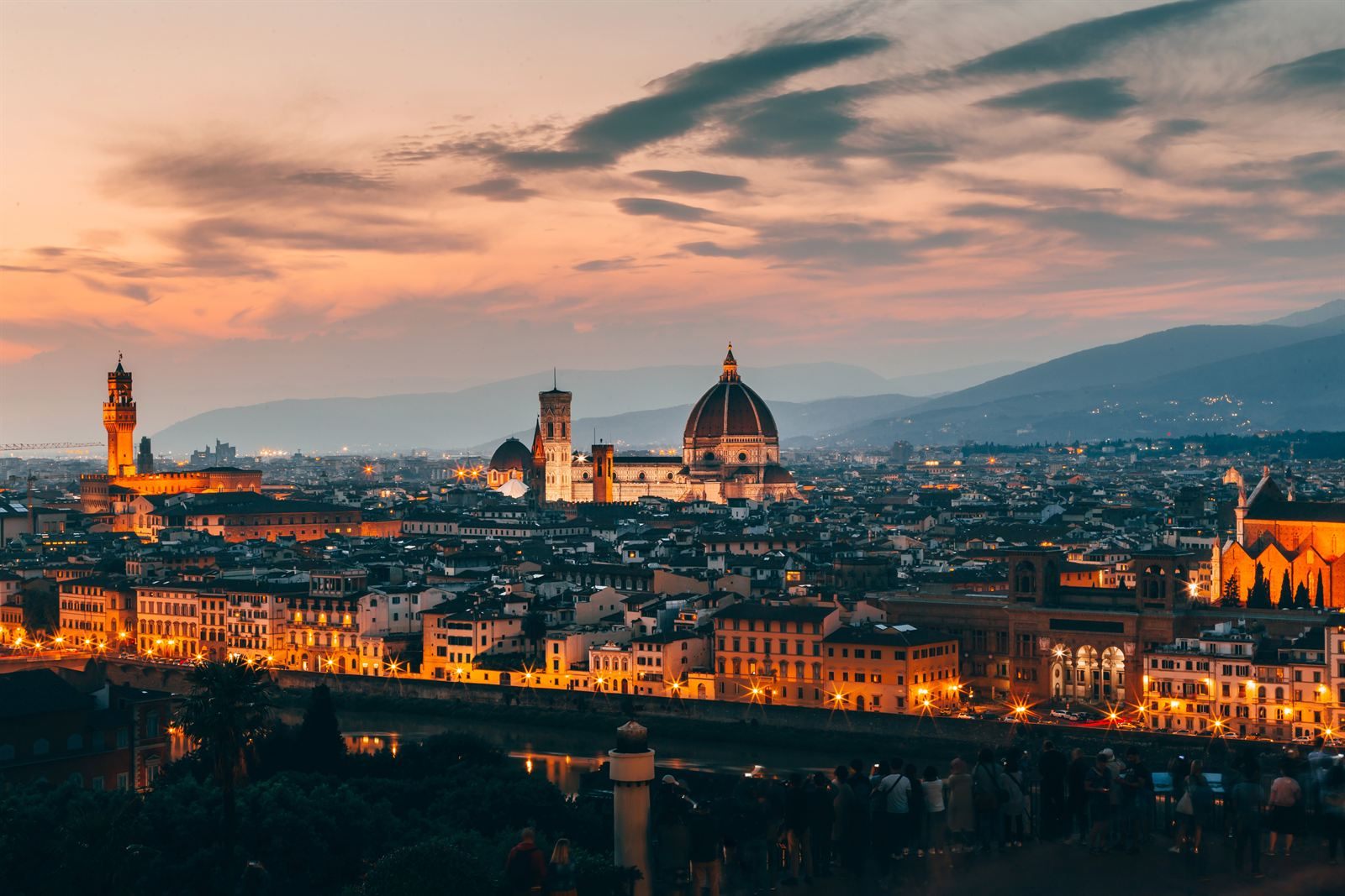 Florence at dusk with the cathedral dome and the tower of the Palazzo Vecchio above the city lights