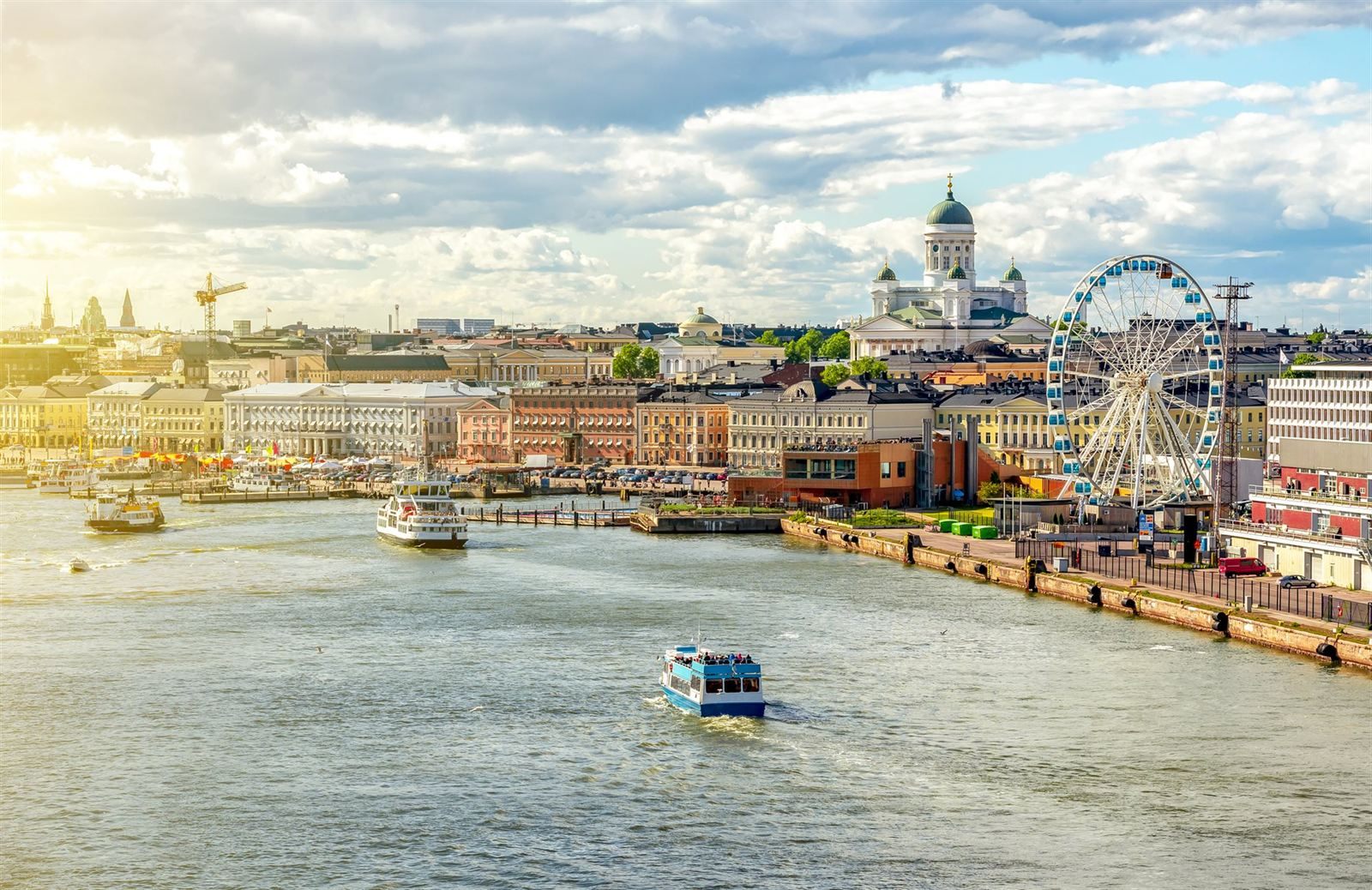 Helsinki harbor with a Ferris wheel, waterfront buildings and the green-domed cathedral above